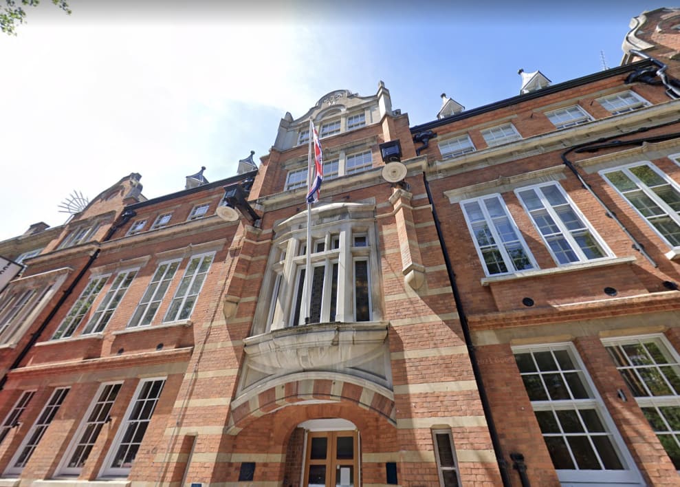 A photo of Eccleston Place against blue sky, a grand brick building with a British flag hanging from a window