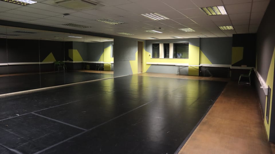 Theatre Deli’s dance studio with a dance floor and grey and green abstract shapes on the wall.