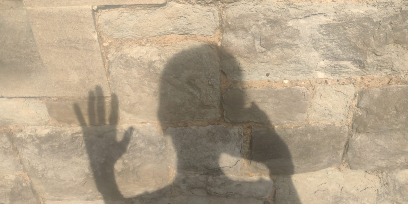 A shadow of a head and hand on a pavement