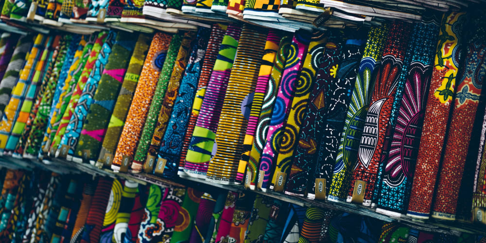 Rows of rolls of bright and colourful fabrics hang up in a fabric shop