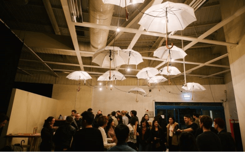 A photo of a group of people socialising at The Eyre Street Theatre Deli venue, underneath white umbrellas and lights hanging from the ceiling