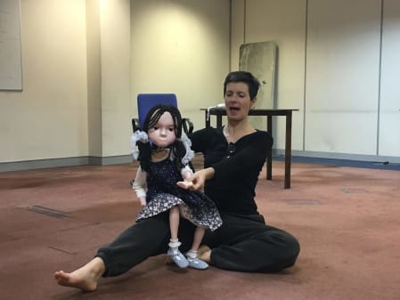 A photo of a woman sitting with a puppet in an indoor space