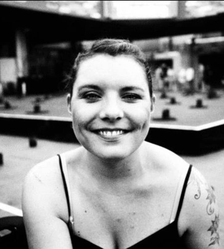 a black and white image of Charlotte. She is a white woman with slicked back blond hair and is smiling at the camera.