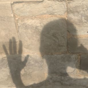 A shadow of a head and hand on a pavement 
