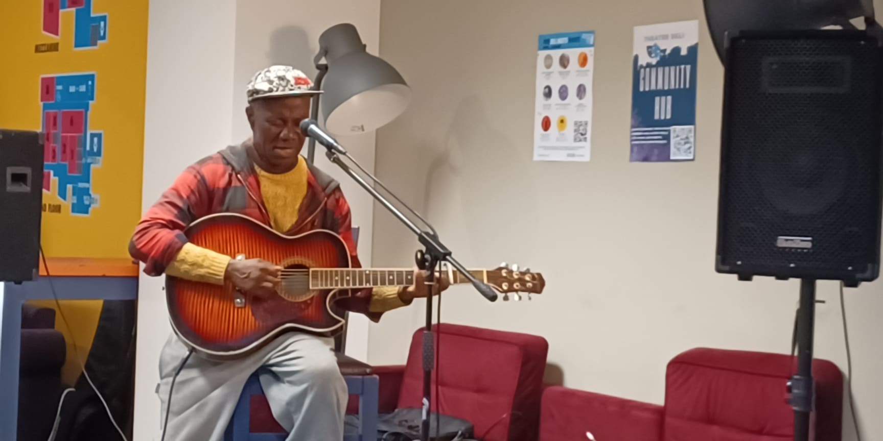 A Black man plays guitar in the Deli Bar and Cafe