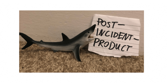 Linke to Post Incidient Product page. A small toy shark on a brown carpet against a white wall. Next to its open mouth is a piece of white lined paper, with the words “POST INCIDENT PRODUCT” written on it in Sharpie.
